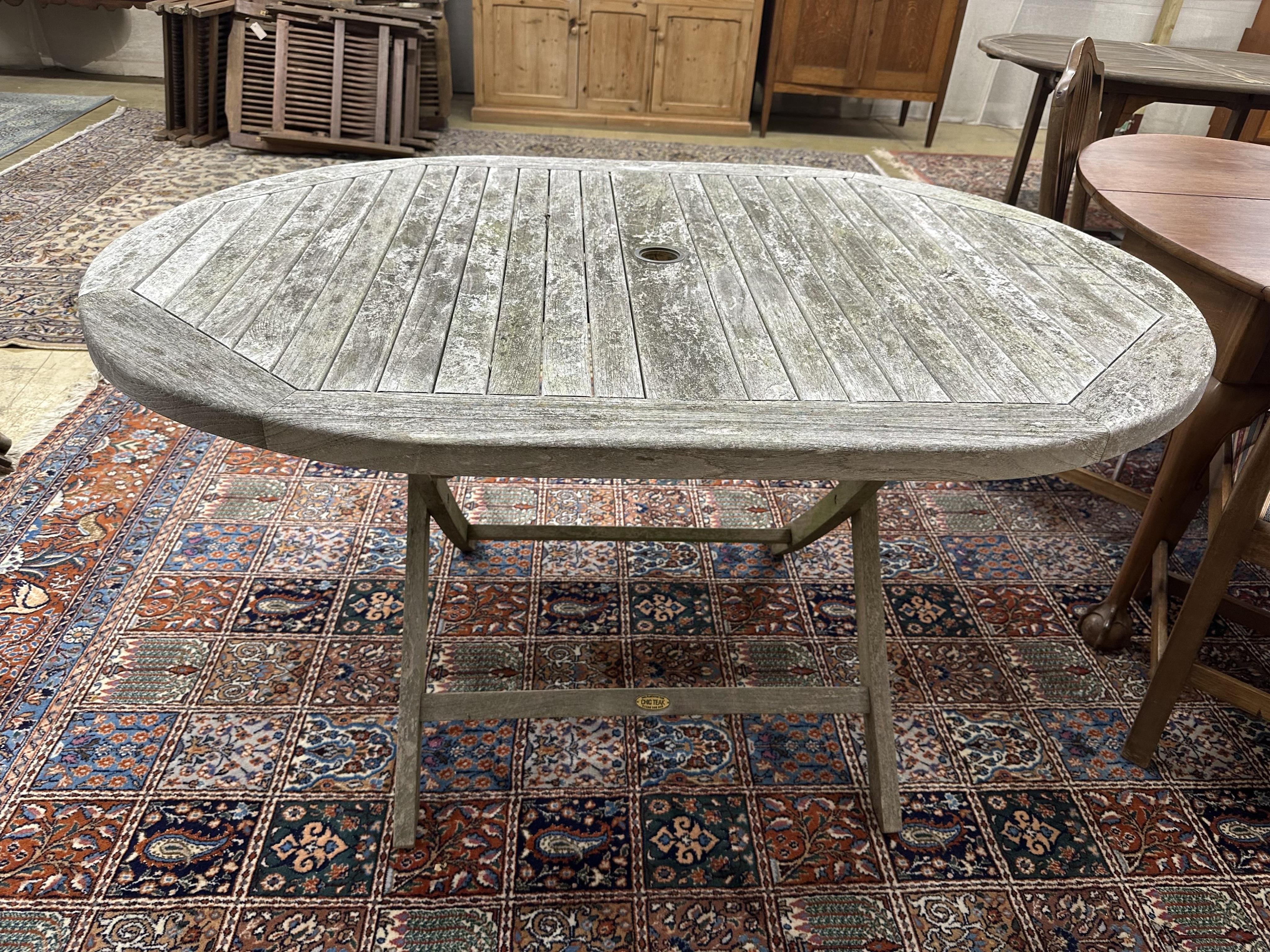 An oval weathered teak folding garden table, width 140cm, depth 100cm, height 76cm, together with six teak folding chairs, two with arms. Condition - fair